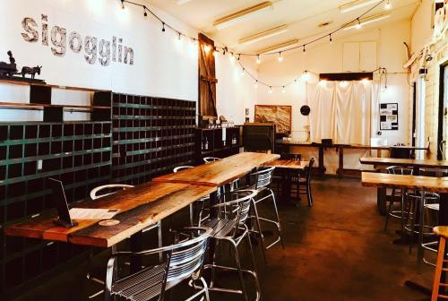 A cozy interior of a café with wooden tables, metal chairs, and string lights, featuring a rustic decor.