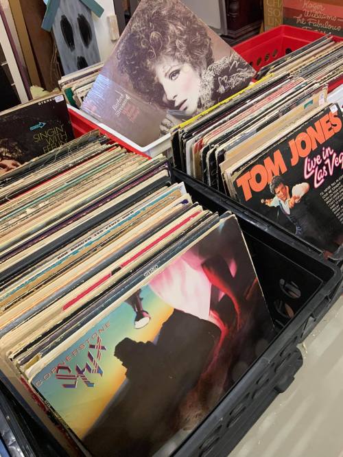 A collection of vinyl records in crates, featuring various album covers, including one with a woman's portrait.