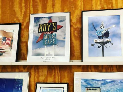 Framed vintage signs for Roy's Motel Cafe and Crossroads, displayed on a wooden wall.