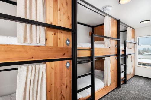Interior of a modern bunk room with wooden frames, two sets of bunk beds, and curtains for privacy.