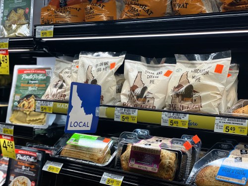 A grocery store shelf displaying various frozen pies and local products, with price tags and a "LOCAL" sign.