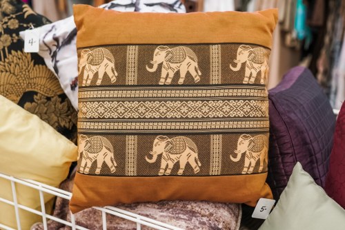 Decorative pillow featuring a brown and gold elephant pattern on a textured background.