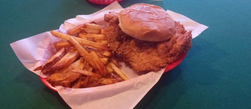 A plate with a crispy fried chicken sandwich and a side of golden, seasoned French fries.