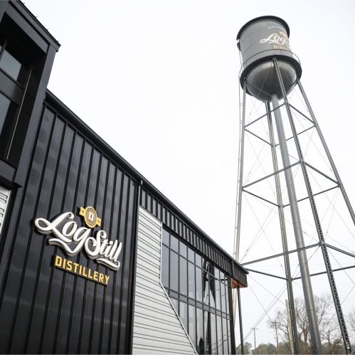 Exterior of LogStill Distillery featuring a modern building and a tall water tower.