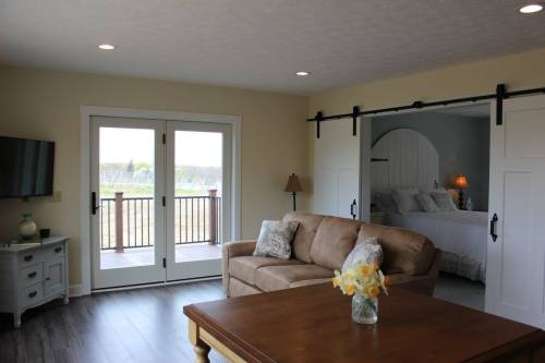 Cozy living area with a sofa, coffee table, and sliding doors leading to a balcony, featuring a bedroom in the background.