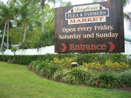 Sign for Daytona Flea & Farmers Market, indicating entrance and open days: Friday, Saturday, and Sunday.