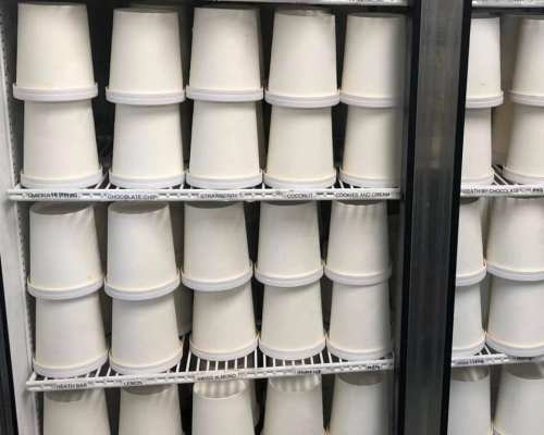 A freezer filled with stacked ice cream containers in various flavors, neatly organized on shelves.