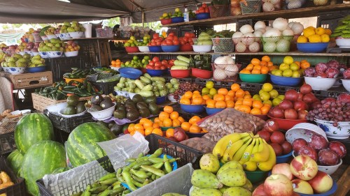A vibrant market display featuring a variety of fresh fruits and vegetables in colorful baskets and bowls.