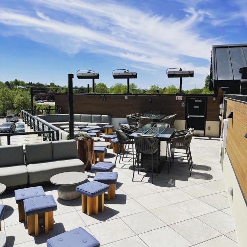 Rooftop patio with modern seating, tables, and a clear blue sky in the background.