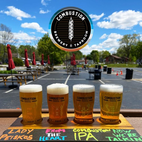 Four glasses of beer on a table, with a brewery logo above and a sunny outdoor setting in the background.