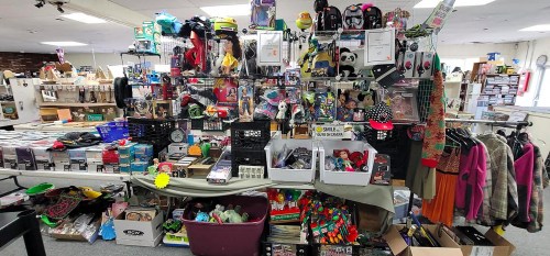 A cluttered display of various items for sale, including toys, clothing, and accessories in a retail space.