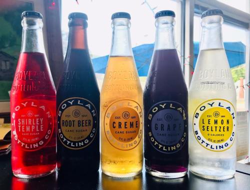 Four glass bottles of Boylan soda: Shirley Temple, Root Beer, Creme, and Lemon Seltzer, displayed on a table.