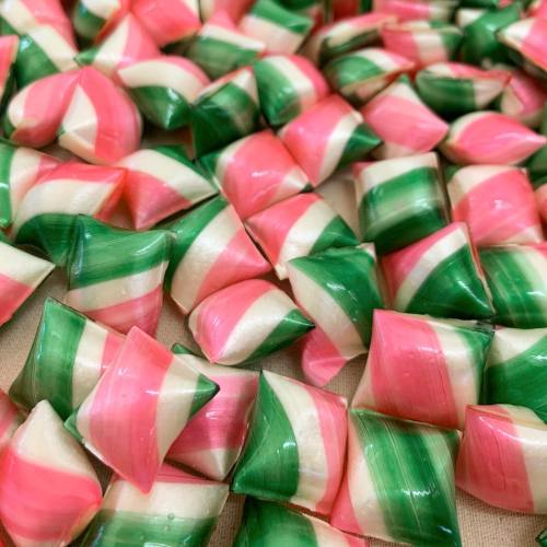 A colorful assortment of twisted candies in pink, green, and white, arranged closely together.