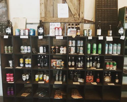 A wooden shelf displaying various bottles and cans of beer, labeled with prices and a sign that says "Mix & Match."