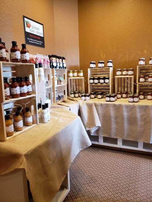 A cozy shop interior displaying shelves of jars and bottles on tables covered with burlap.