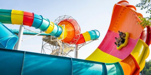 A colorful water slide with riders in a yellow inner tube, surrounded by bright blue and orange structures.