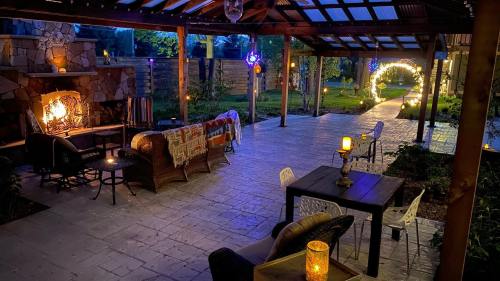 Cozy outdoor patio at night, featuring a stone fireplace, seating, and soft lighting along a garden path.
