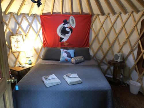 Cozy yurt interior with a bed, penguin-themed decor, and warm lighting. Towels neatly arranged on the bed.