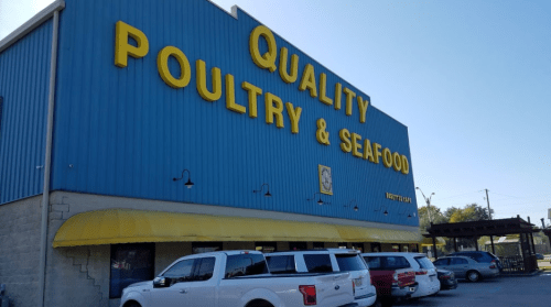 Exterior of a blue building with a yellow awning, featuring a large sign that reads "Quality Poultry & Seafood."