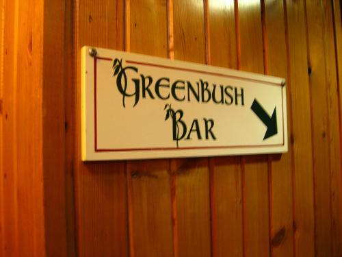 Sign for "Greenbush Bar" with an arrow pointing left, mounted on a wooden wall.