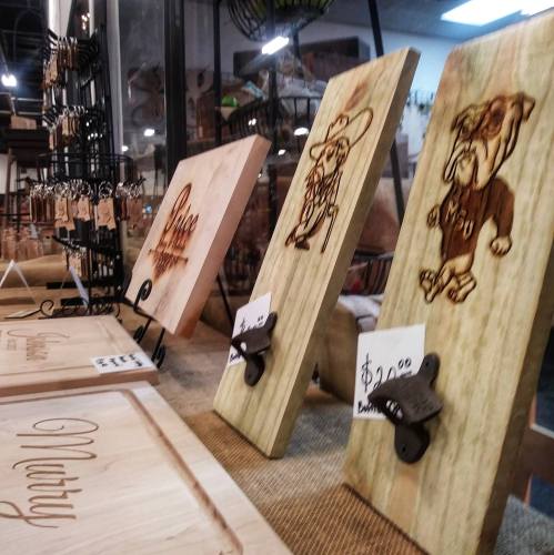 Wooden plaques with engraved designs of a cowboy and a bulldog, displayed for sale in a craft shop.