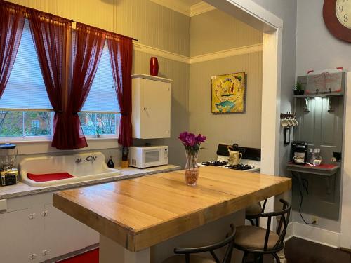 Cozy kitchen with a wooden table, red curtains, and modern appliances, featuring a vase of flowers on the table.