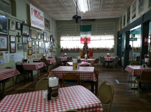 Cozy restaurant interior with checkered tablecloths, framed photos on the walls, and a festive holiday decoration.