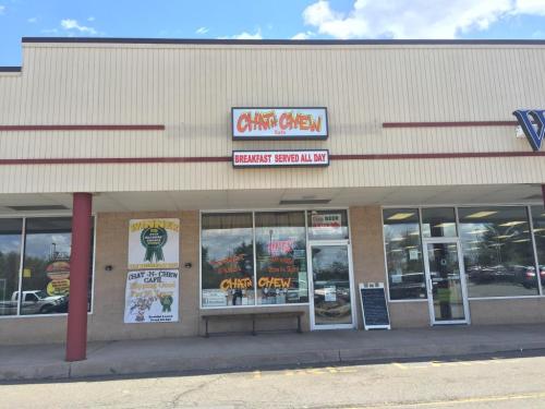 Exterior of Chit 'n' Chew Cafe, featuring a sign for breakfast served all day and various promotional banners.