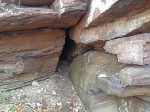 A narrow passageway between large, weathered rock formations in a natural setting.