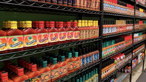 A colorful display of various hot sauce bottles arranged on shelves in a store.