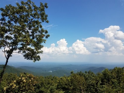 A scenic view of rolling green mountains under a blue sky with fluffy white clouds.
