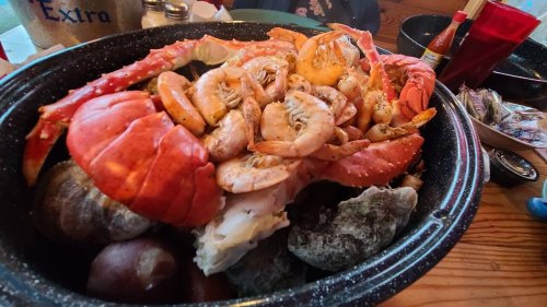 A large seafood platter featuring crab, shrimp, and various shellfish served in a black bowl.