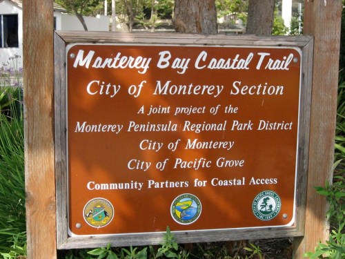 Sign for the Monterey Bay Coastal Trail, detailing partnerships for coastal access in Monterey and Pacific Grove.