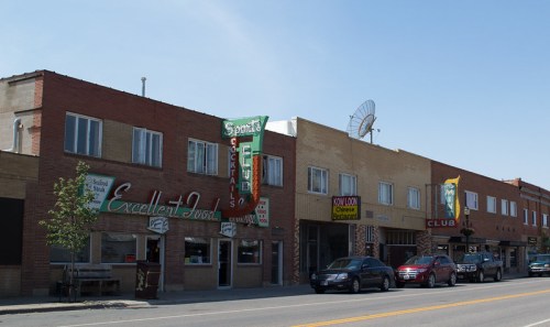 A street view of a small town featuring vintage storefronts, including a bar and a Chinese restaurant.