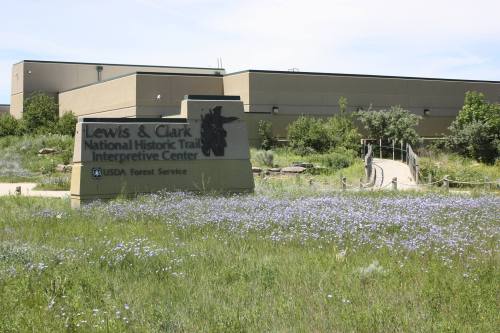 Sign for the Lewis & Clark National Historic Trail Interpretive Center, surrounded by a grassy field with flowers.