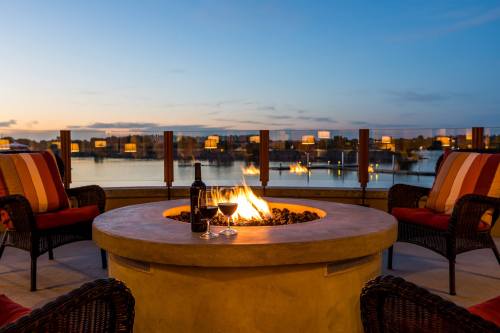 Cozy outdoor seating with a fire pit, wine glasses, and a scenic view of a lake at sunset.