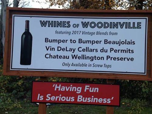 Sign advertising "Whines of Woodinville" featuring 2017 vintage blends and a playful tagline about having fun.
