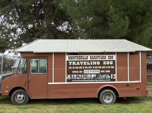 A brown food truck with a sign for Montebello Barnyard Zoo, advertising a traveling zoo and petting zoo services.
