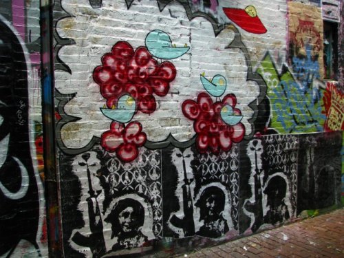 Colorful street art featuring flowers, birds, and abstract patterns on a brick wall.