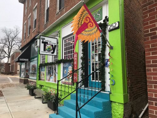 Colorful storefront of a toy company with a vibrant sign and decorative elements, featuring stairs and a welcoming entrance.