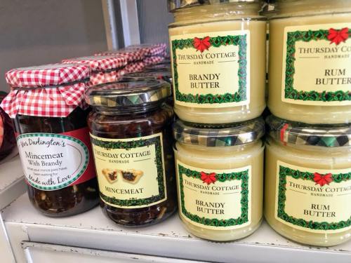 Jars of mincemeat and brandy butter on a shelf, featuring decorative labels and a checkered lid on one jar.