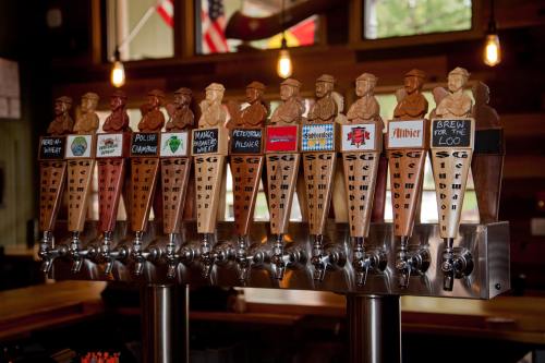 A row of beer taps with unique wooden handles featuring various designs and labels in a rustic bar setting.