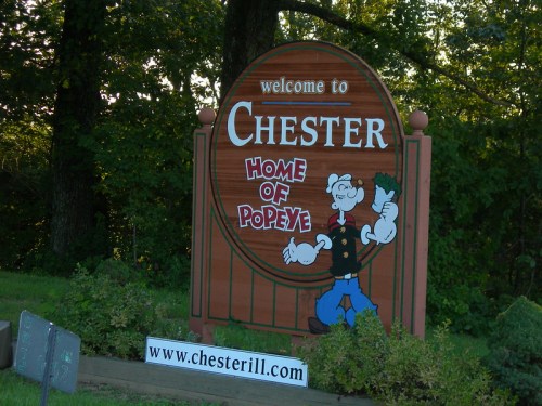 Sign welcoming visitors to Chester, featuring "Home of Popeye" and an illustration of Popeye holding a spinach can.