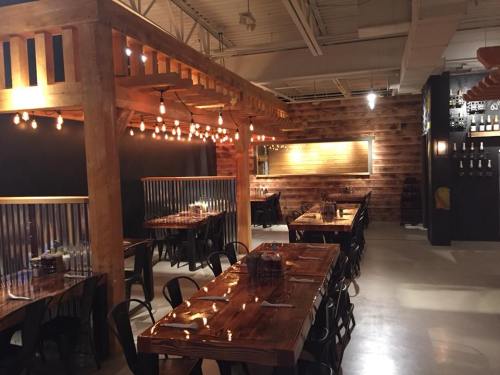 Cozy restaurant interior with wooden tables, string lights, and a rustic decor featuring dark walls and a bar area.