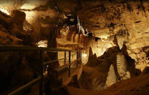 A dimly lit cave interior with rock formations and a pathway, showcasing natural textures and shadows.