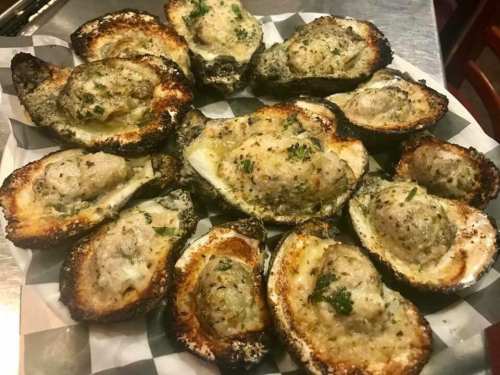 A platter of baked oysters topped with a golden, herb-seasoned stuffing, garnished with parsley.
