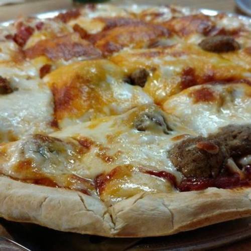 A close-up of a cheesy pizza topped with sausage and pepperoni on a golden crust.