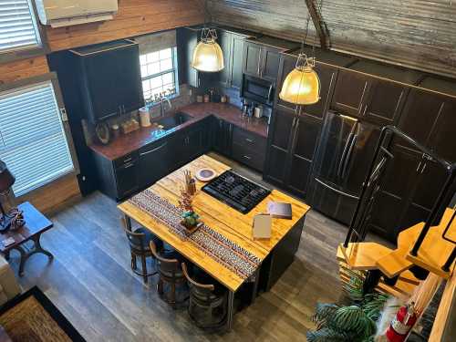 Aerial view of a modern kitchen with dark cabinets, a large wooden island, and pendant lighting.