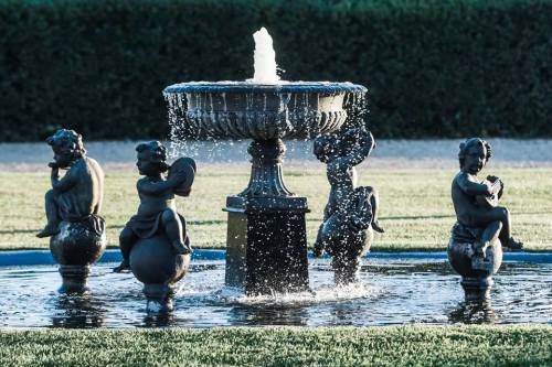 A decorative fountain featuring four cherubic statues, water cascading from the center into a circular basin.