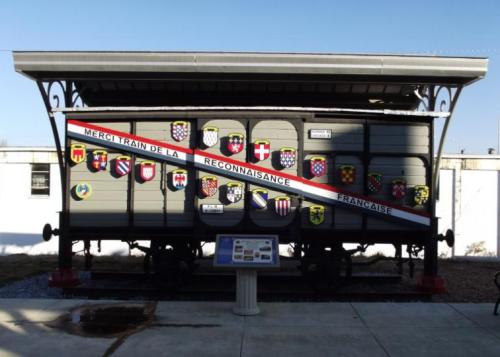 A historic train car adorned with various shields and a banner reading "Merci train de la reconnaissance française."